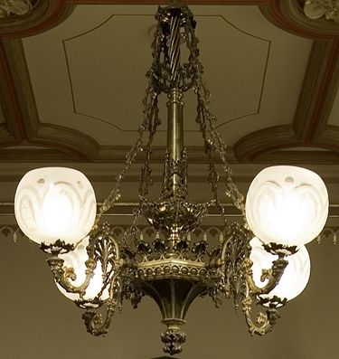 A four branch chandelier with tracery on each branch and large glass ornaments