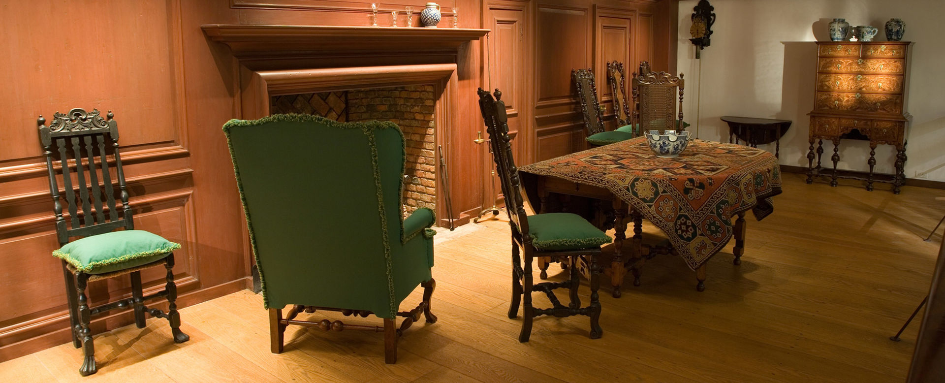 A green easy chair and a dining table draped with fabric installed in the Wentworth Room at The Met