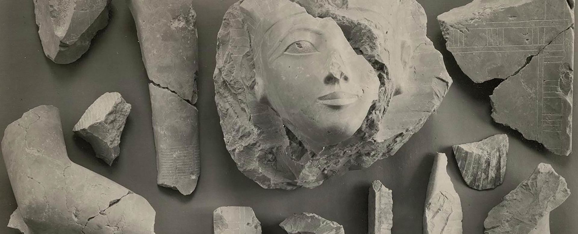 Black-and-white photo of various pieces of a statue of Hatshepsut disassembled