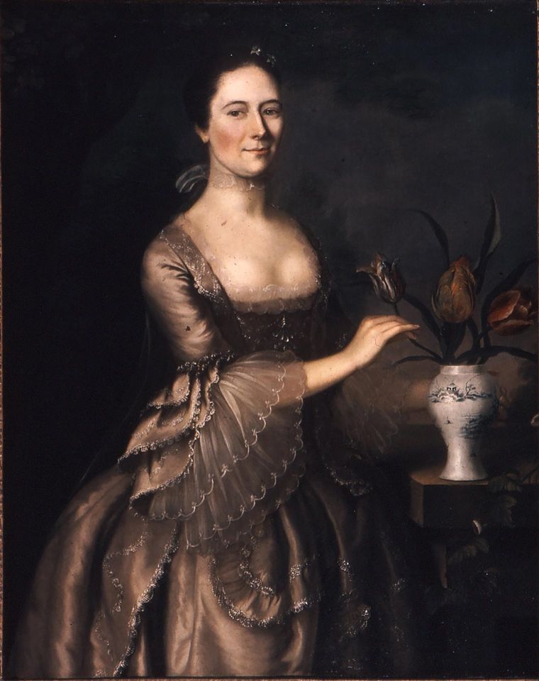 Painting of a woman in a silk brown dress with lace detailing posing next to a vase of tulips.