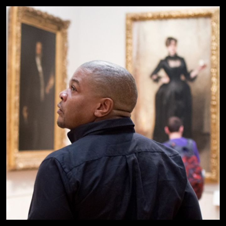Man in American paintings gallery turning to look at a painting on his left
