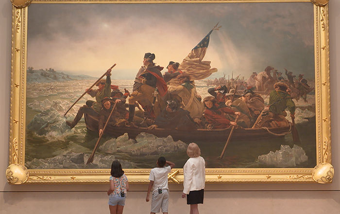 Adult curator Betsy Kornhauser and two kids named Gaia and Carmelo look at the painting Washington Crossing the Delaware at The Met. Their small figures are dwarfed by the large painting.