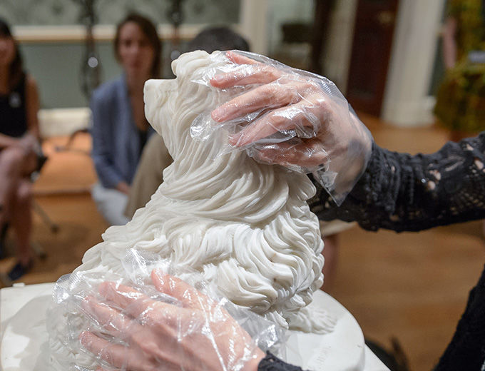 A visitor who is blind feels a sculpture through protective gloves