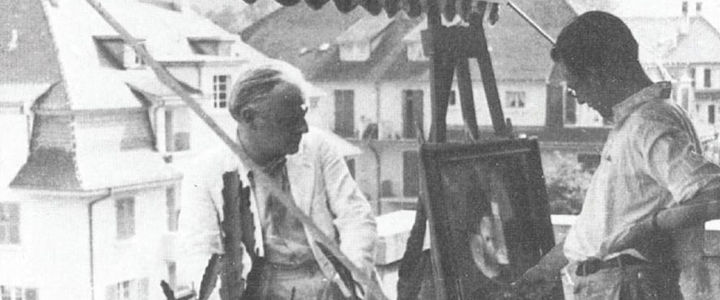 Black-and-white photo of the artist Paul Klee sitting on a balcony while his son, Felix Klee, looks at a painting