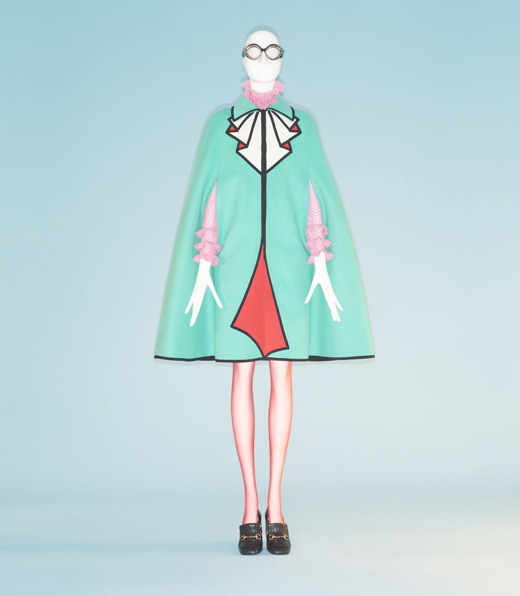 Couture jacket featuring a mint-green base and adorned with red and gold fabrics and peek-a-boo arm holes