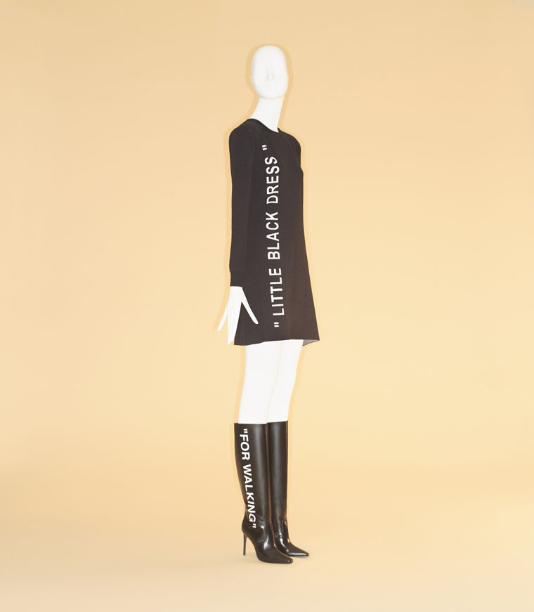 Black form-fitting dress with the text "Little Black Dress" embroidered along the side and black knee-high boots with the text "For Walking"