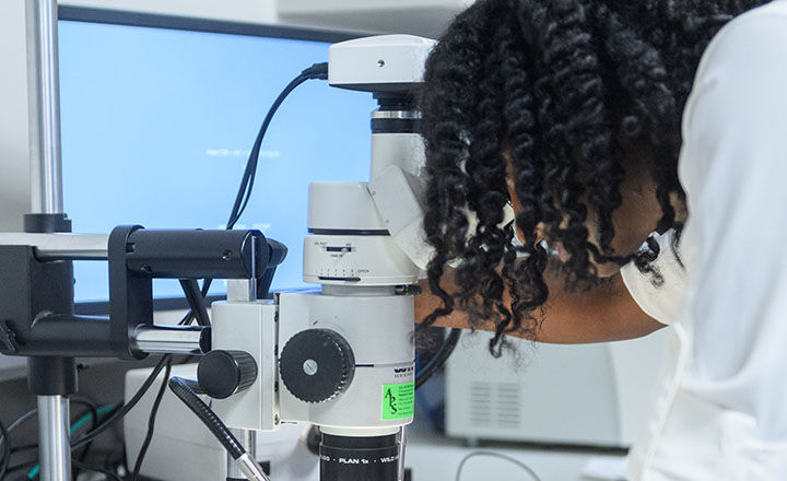 A woman a lab using a microscope