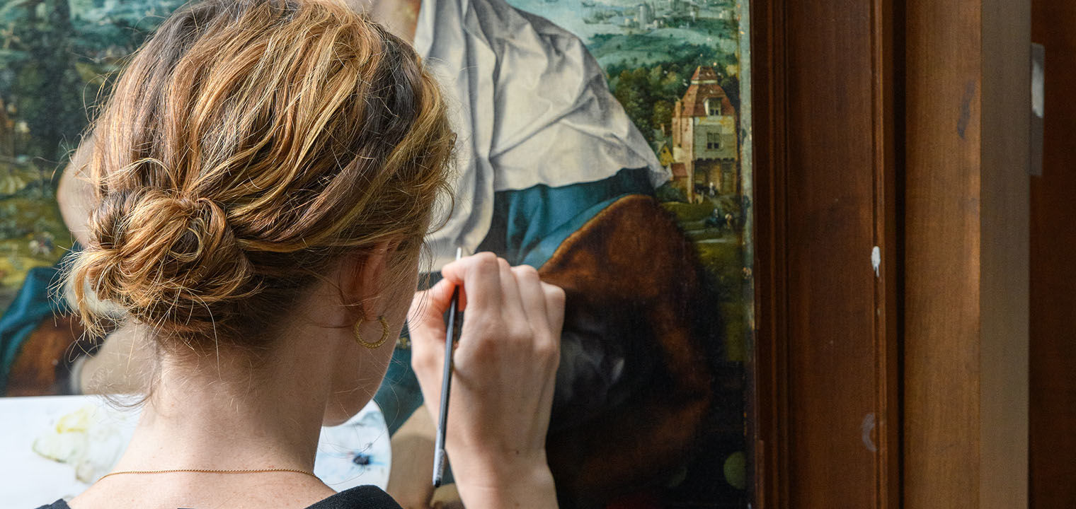 A woman works on a painting with a brush