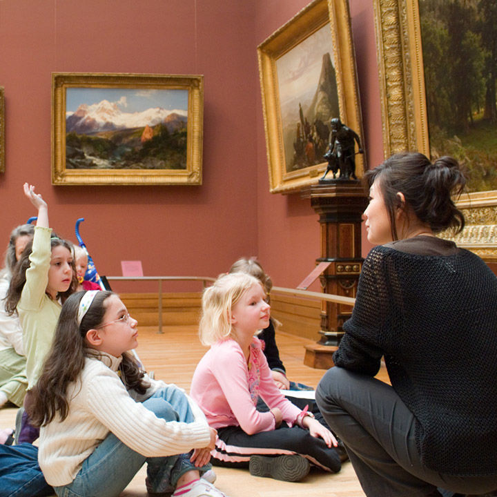 A student from one of the school groups raises her hand in the middle of a gallery
