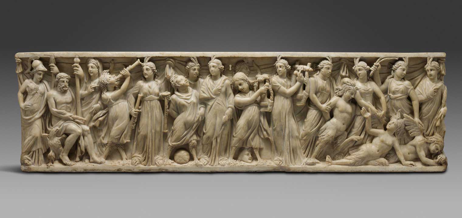 A white stone high relief carved sarcophogus depicting a group of women in classical dress holding various artistic or musical instruments, triumphing over three women with mermaid tails and wings, who have been pushed to the ground