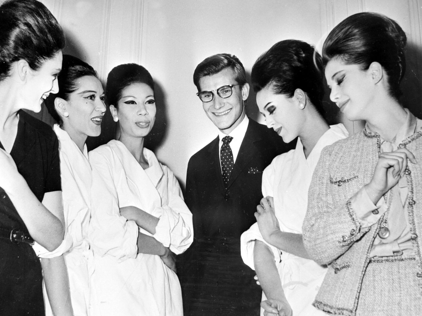 Yves Saint Laurent poses smiling next to five models