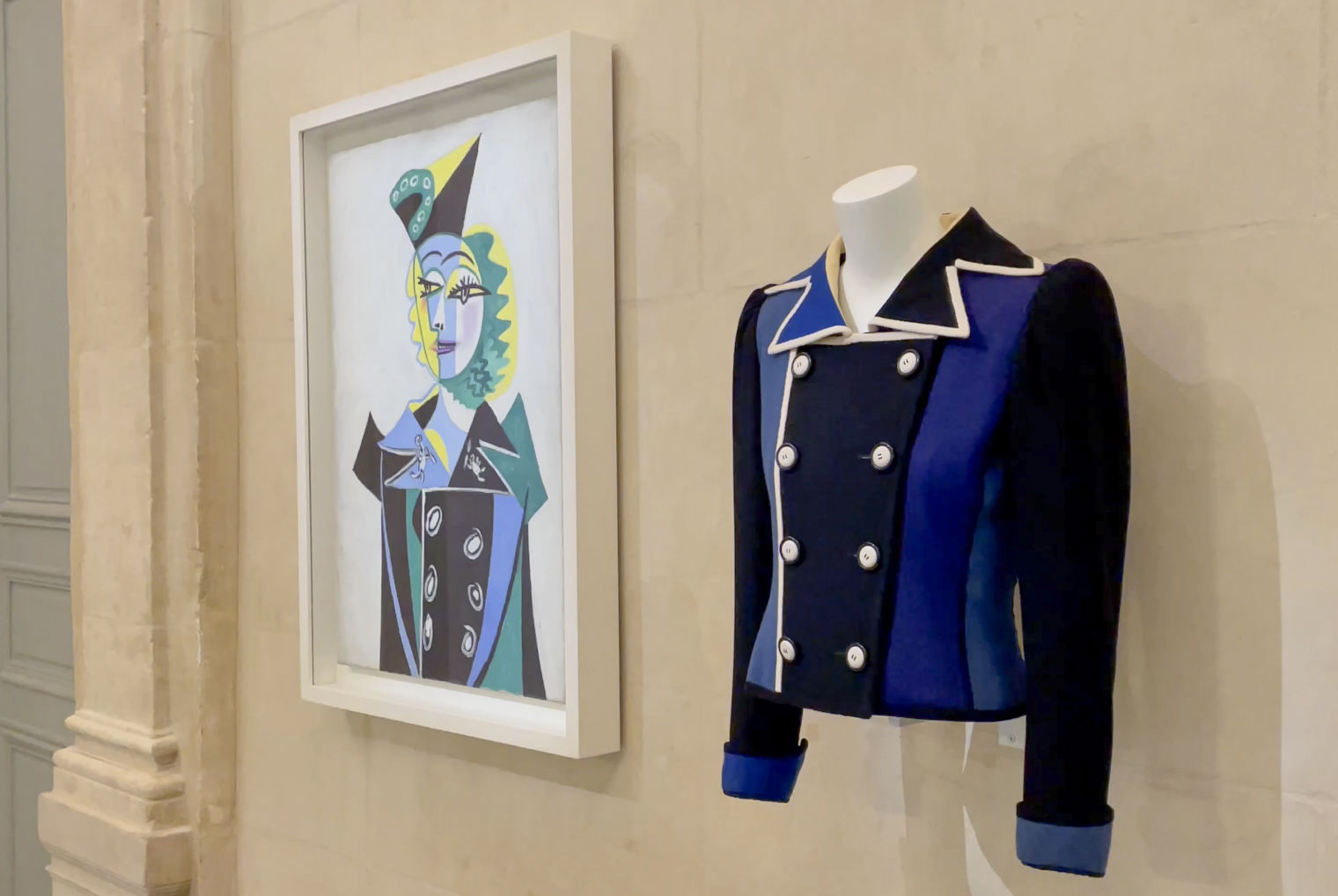 Exhibition photograph showcasing a Picasso-inspired jacket designed by Yves Saint Laurent and a portrait of Nush Eluard by Picasso