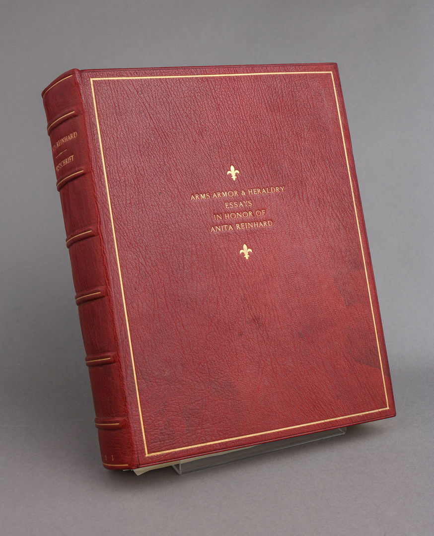 Red book with the title "Arms Armor and Heraldry Essays in honor of Anita Reinhard" in gold letters