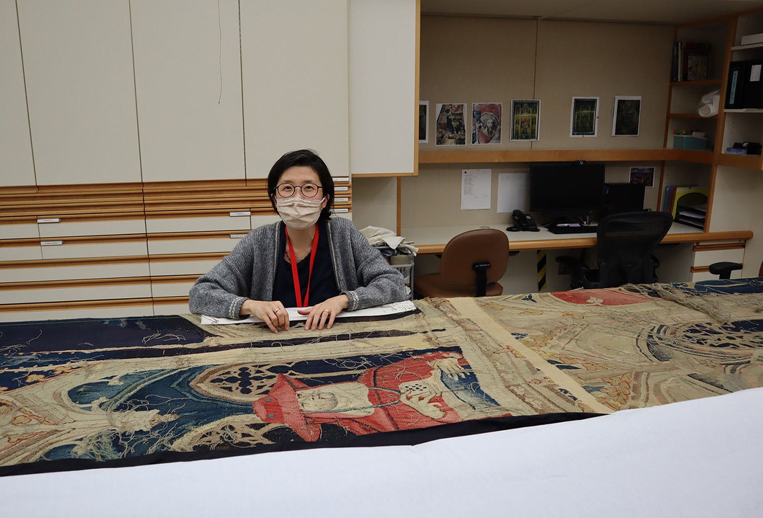 Kisook Suh works on textile artwork on a table.