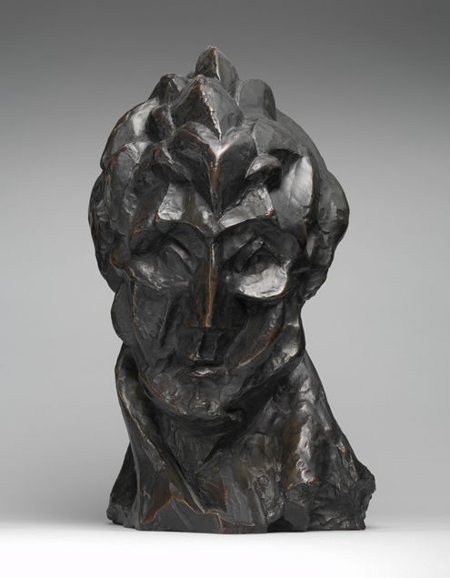 A bronze sculpture of a woman's face made out of rigid lines, her eyes pointed down
