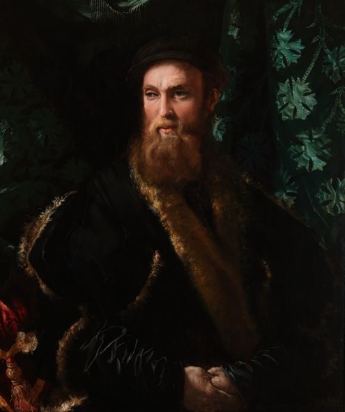 Portrait of a man, waist-up, with dramatic lighting across his bearded face. In the background is decorated green drapery.