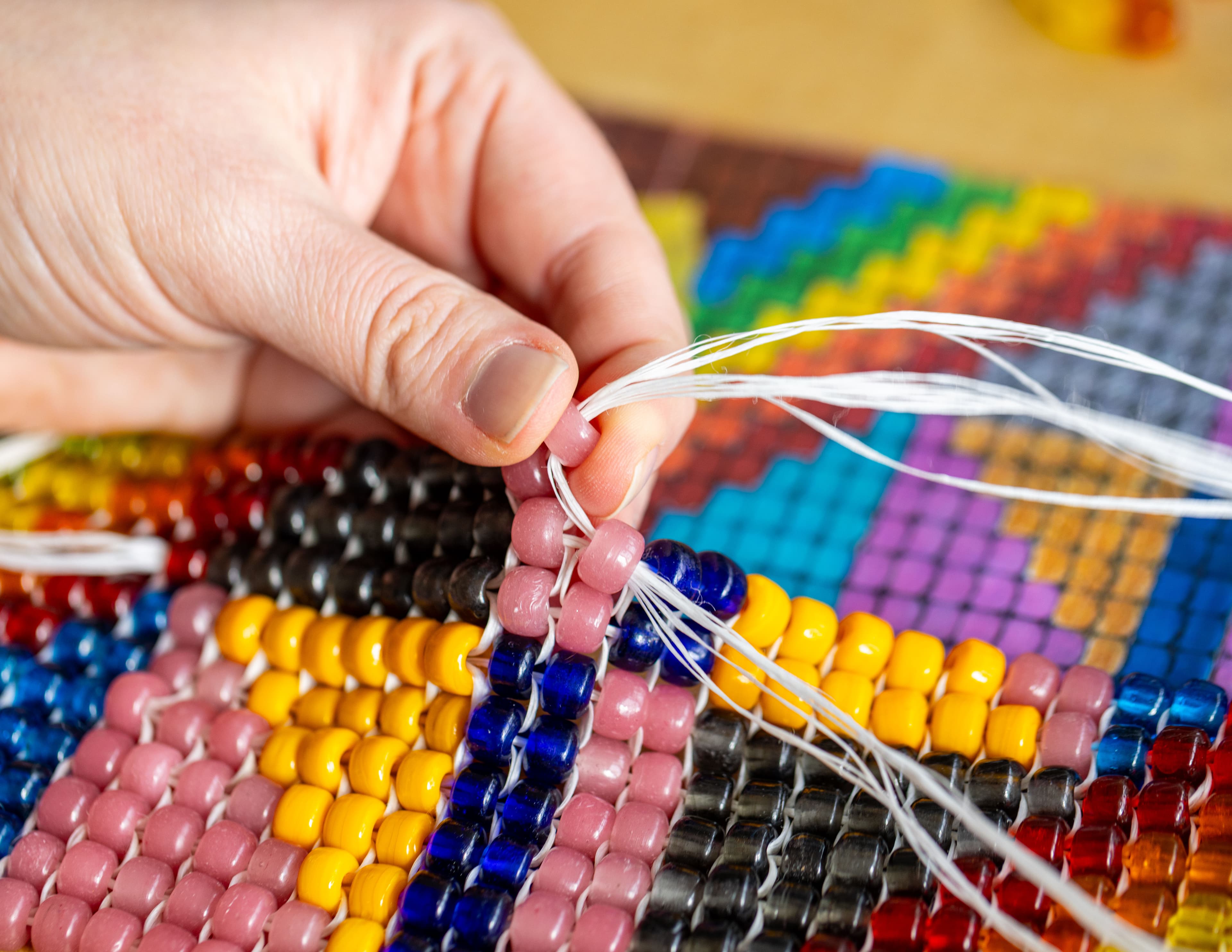 Hands creating a beaded design.