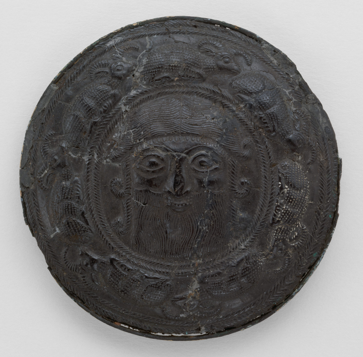 Roundel with the head of a hero surrounded by caprids