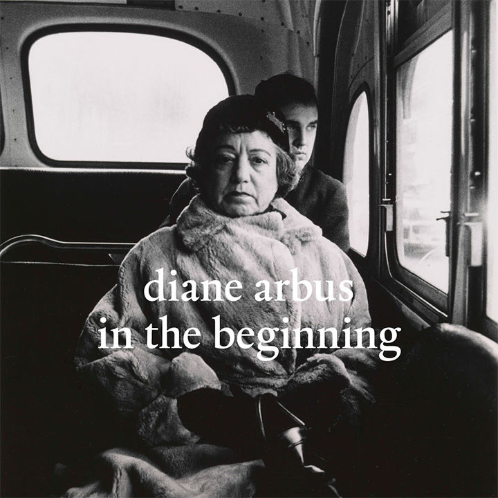 Black-and-white photograph of an older woman dressed in a fur coat seated in the back of a bus, in front of a younger man looking out the window behind her; the photograph includes the following overlay text: "diane arbus in the beginning"