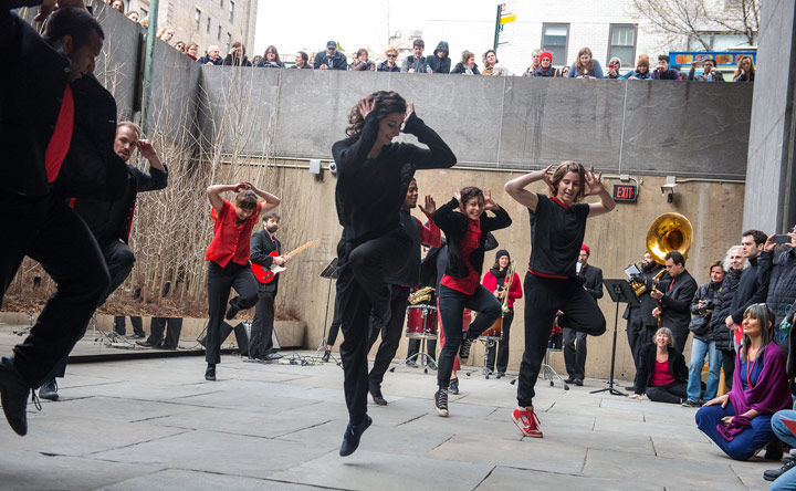 A group of dancers jump in synchrony in a sunken garden at The Met Breuer