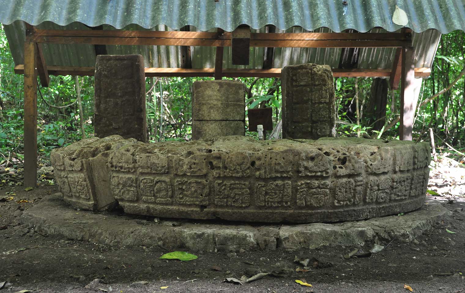 Long horizontal engraved altar stone lying under a protective tent