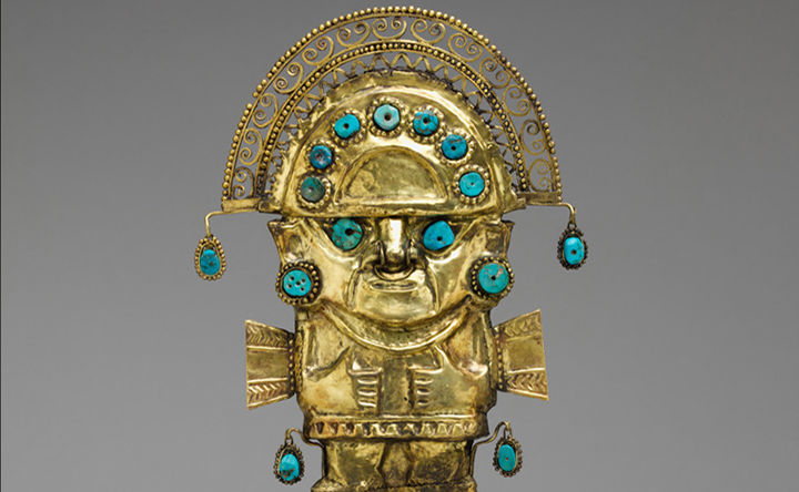 Golden figure with turquoise stones wearing a hat or crown.