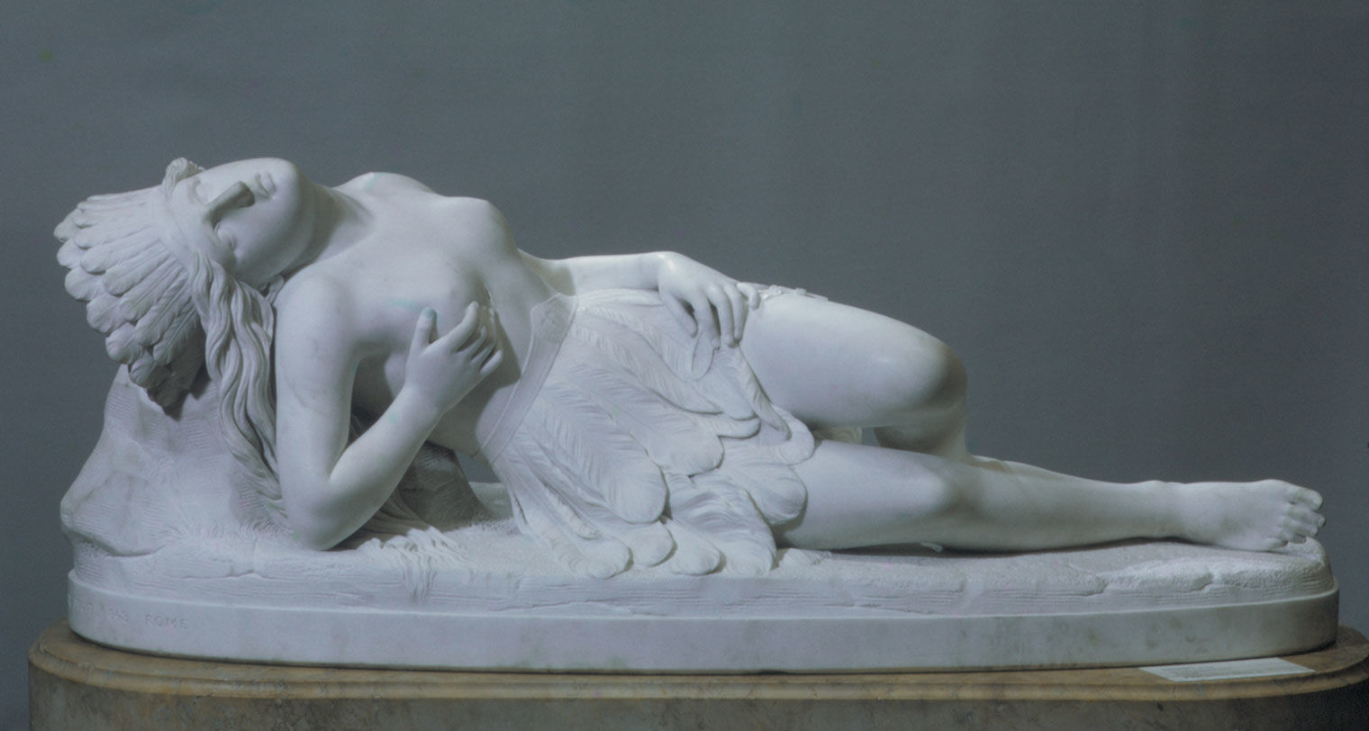 A white marble sculpture of a young, bare-chested woman with a headdress, who rests as if dying