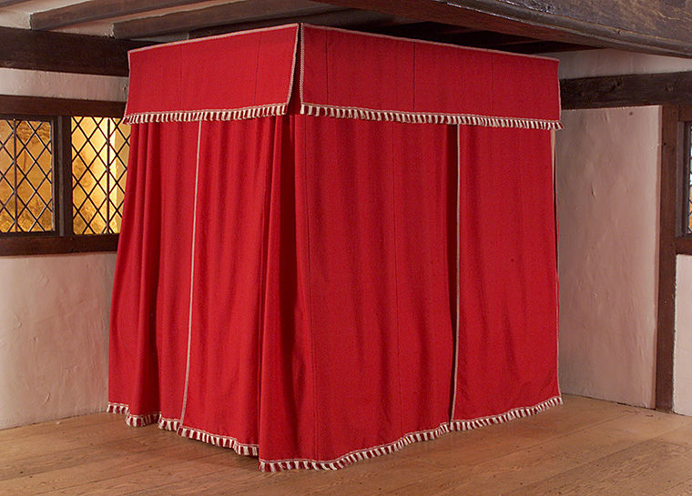 Red bedstead with curtains drawn in the Hart Room