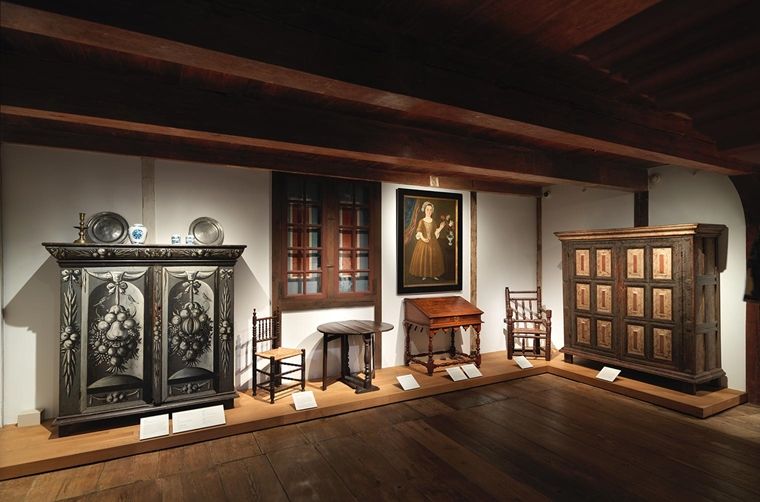Interior view of the New York Dutch Room at The Met, featuring wooden furniture, a window, and a painting of a young girl.