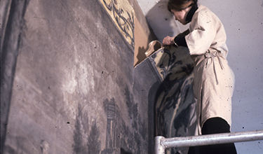 Top: A conservator removing the wallpaper; Bottom: a stamp signifying an English tax