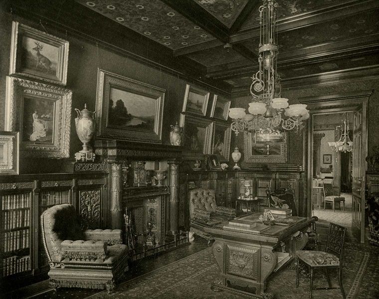 Archival photograph of the library at 4 West 54th Street with a desk, chairs, fireplace, light fixture, and paintings on the wall.