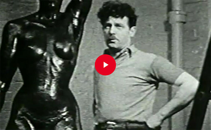 Still from archival video of a sculptor in front of a nude female sculpture of his