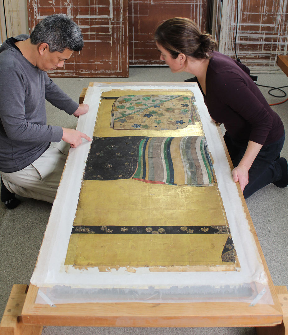 Two conservators kneeling over a Japanese textile