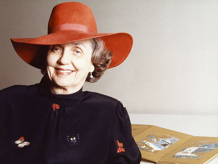Mary Griggs Burke wearing a red hat and a black jacket with red, white, and black butterfly motifs