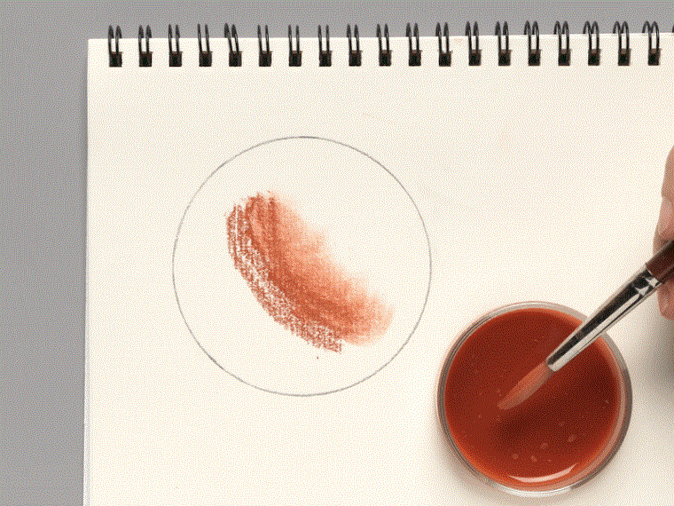 A moving image of a hand wetting a brush in chalk wash and spreading it on paper.