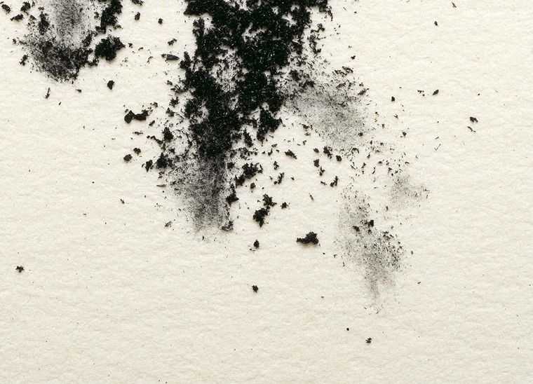 charcoal powder messily scattered over a lightly textured white surface