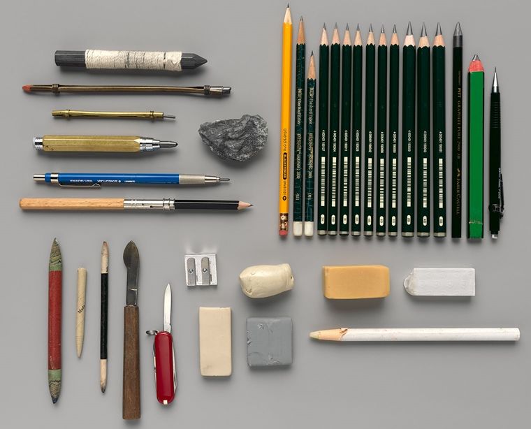 An artful arrangement of pencils, erasers, raw graphite, and other drawing implements.