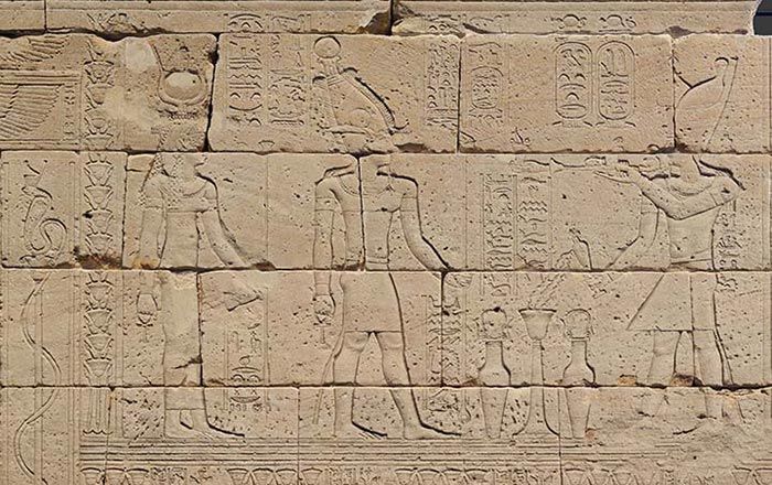 Detail of temple wall depicting Augustus (right) burning incense and pouring milk for the god Osiris (center) and the goddess Isis (left)