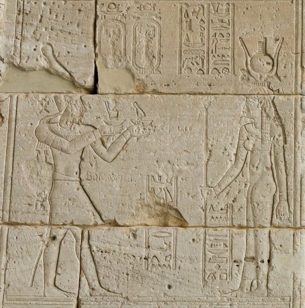 Detail depicting Augustus (left) offering the crowns of Upper and Lower Egypt to the goddess Isis (right). On top of her headdress is a small stepped hieroglyph that depicts a throne and was used to write Isis's name.