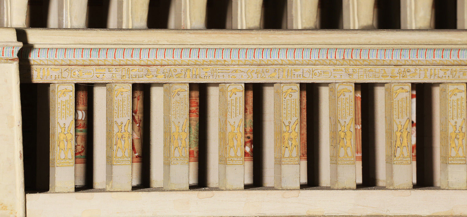 Eight pilasters decorated with crowned figures embracing, under a cornice with red and blue stripes. More pillars can be seen in the gaps between the pilasters.