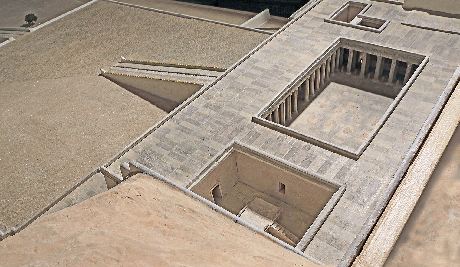 Bird's eye view of the top of a stone building, with a large ramp in front and an altar with a ramp inside.