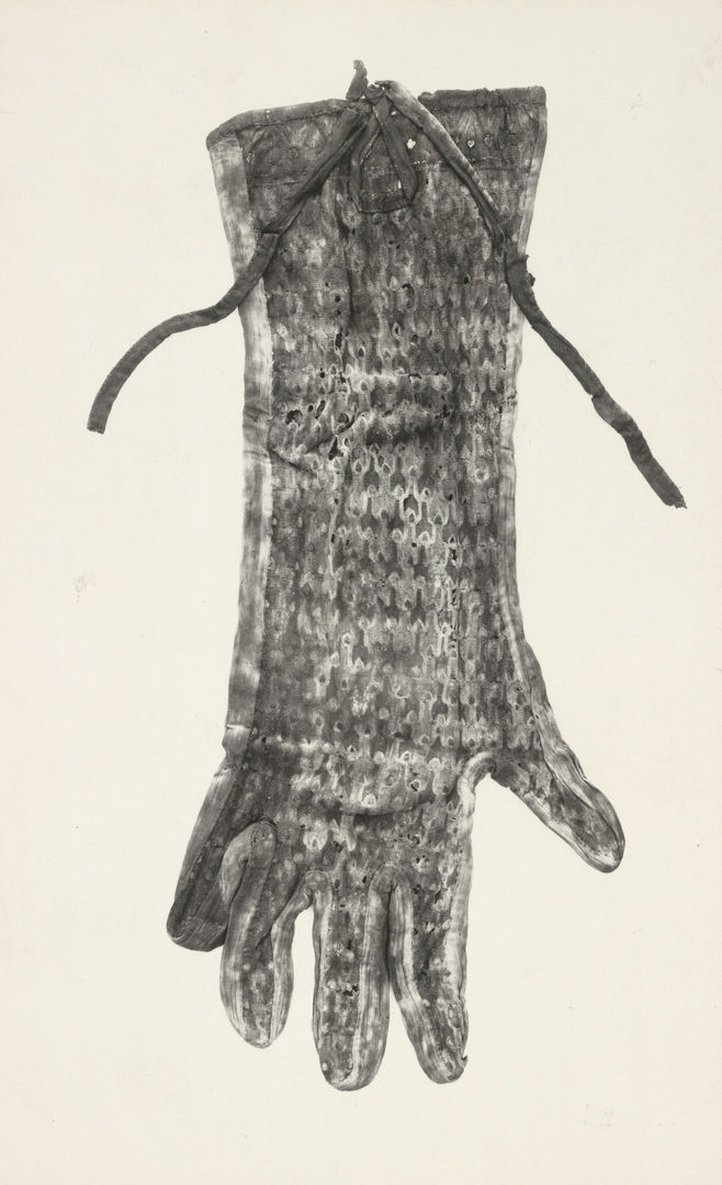 Black and white image of a glove decorated with a feather pattern, with a tie at the opening.