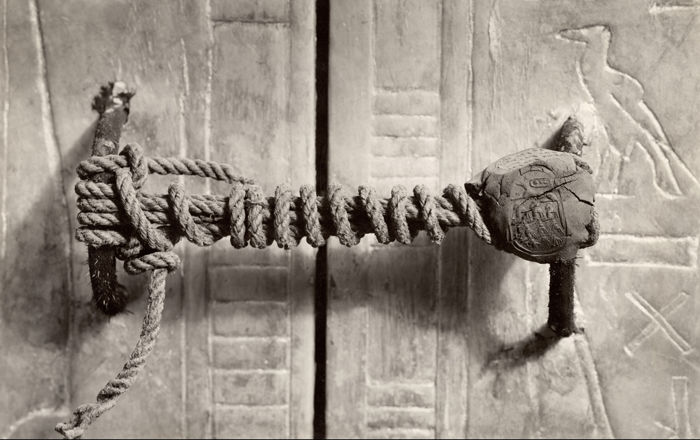 A doorway into one of the shrines of Tutankhamun, tied shut with rope wound around two metal bolts and a lump of clay with the impression of a seal on one side.