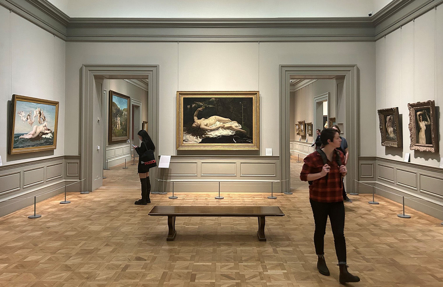 A view of guests looking at artworks in Gallery 811, including Cabanel's "The Birth of Venus", Courbet's "Woman with a Parrot", "The Woman in the Waves", and "Woman with a Flowering Branch".