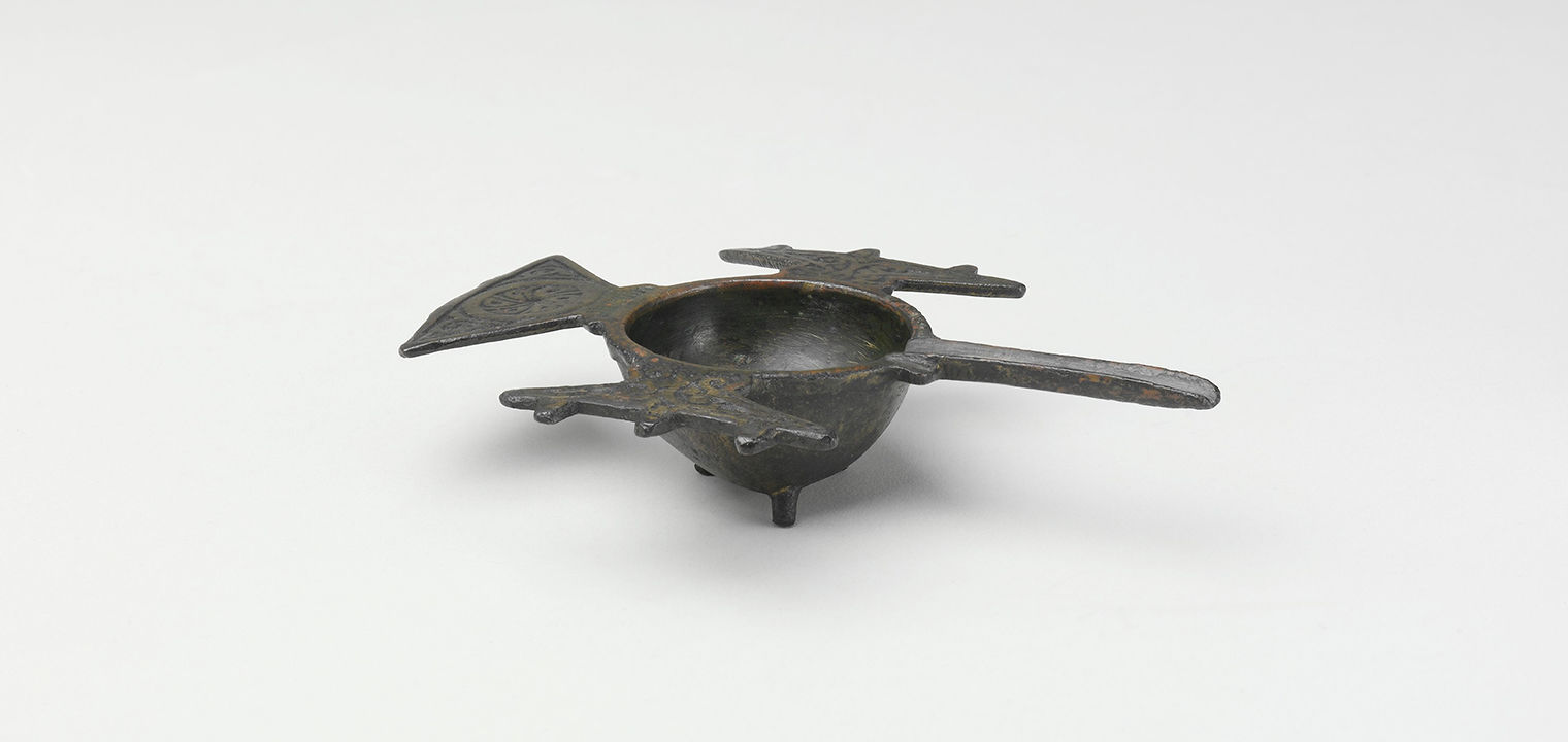 a bronze mortar with a small well, flanged handles and a long horizontal spout