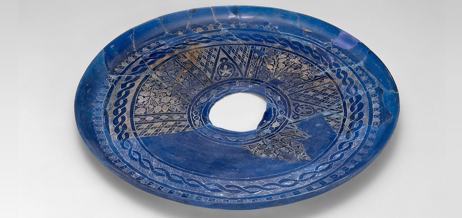 blue glass plate fragment with engraved geometric and vegetal designs