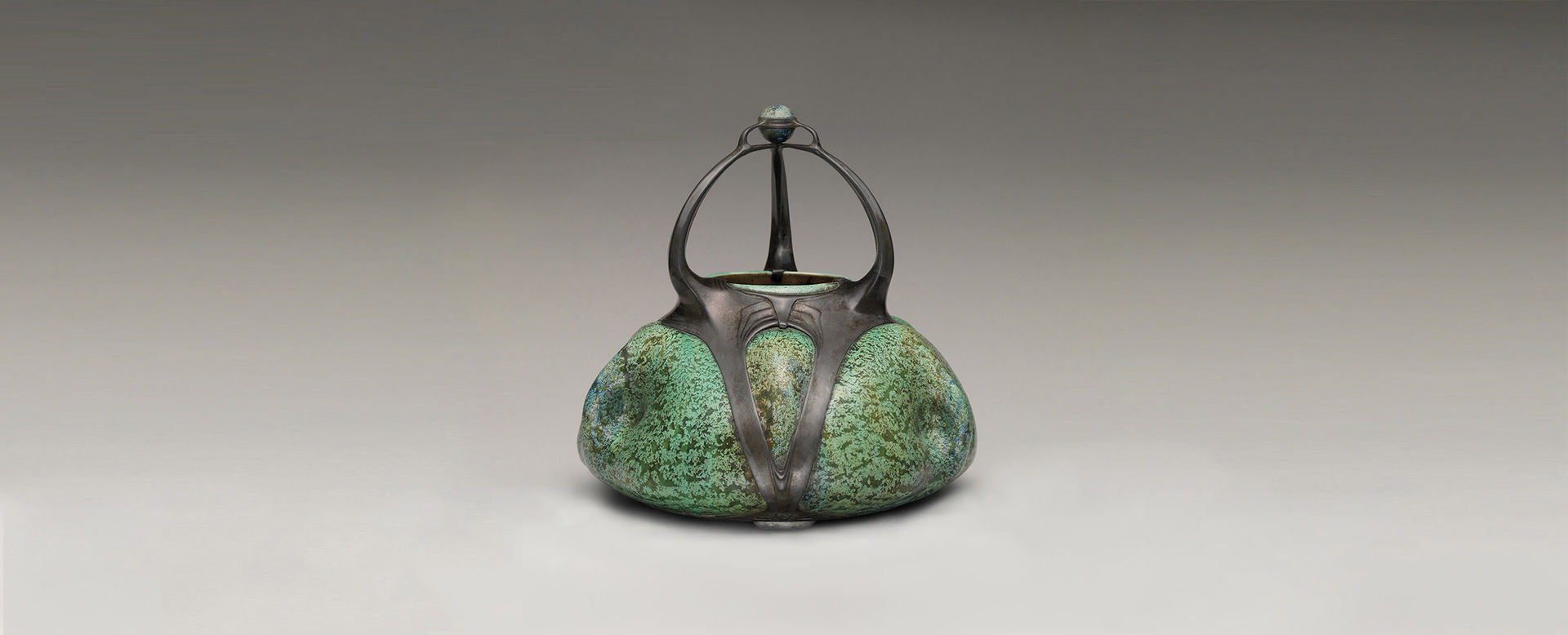 A green tea pot kettle against a grey background