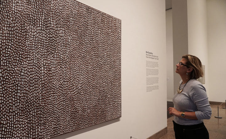 Curator looking up at a piece of Oceanic art on the wall