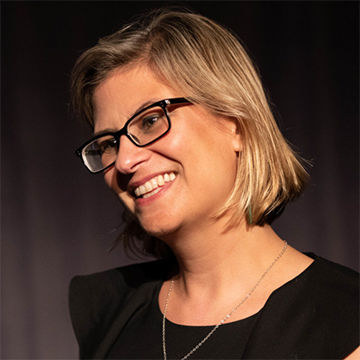 Headshot of Maia Nuku wearing a black shirt and black rectangular glasses