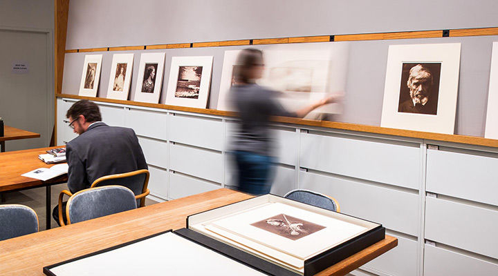 A man and a woman looking at photographs in the Photographs Study Room at The Met